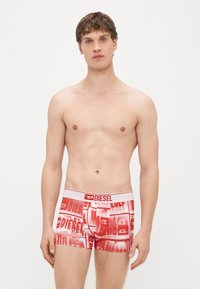 Boxer rossi con una fascia in vita bianca recante il logo "DIESEL". Il materiale è liscio, con un motivo ripetuto in diverse tonalità di rosso.