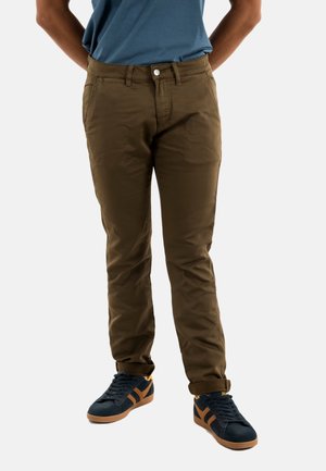 Chinos en coton marron avec une coupe slim, dotés de poches avant, d'une fermeture à bouton et de manches roulées, associés à des baskets navy.