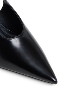 Escarpin en cuir verni noir à bout pointu avec un design découpé. Texture lisse et finition brillante, avec des coutures minimales le long du bord.
