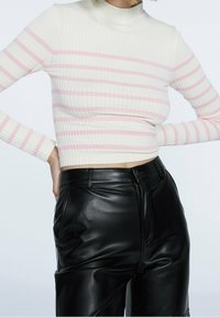 Långärmad, figurnära turtleneck-tröja i ribbad tyg, i krämfärg med rosa horisontella ränder; matcher med svarta faux läderbyxor.