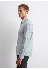 Light blue patterned long-sleeve shirt with a button-down collar, featuring a subtle geometric design and a single chest pocket on the left.