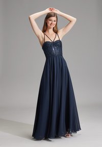 Lungo abito blu navy con corpetto decorato di perline e spalline sottili, caratterizzato da una gonna fluente che scende elegantemente fino a terra.