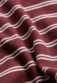 Material moale de culoare burgund cu textură fină nervurată și dungi orizontale subțiri albe, distribuite uniform, prezentat cu pliuri delicate.