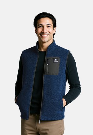 Navy fleece vest with textured pattern, zippered chest pocket in black, and front side pockets. Worn over a black long-sleeve shirt.