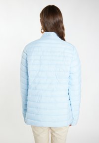 Giacca a vento leggera azzurra con texture trapuntata, colletto alto e dettagli a costine, caratterizzata da una vestibilità rilassata e tessuto morbido.