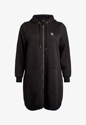 Black quilted long zip-up hoodie with front pockets, drawstring hood, ribbed cuffs, and a small geometric logo on the chest.