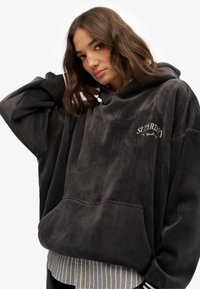 Sudadera de gran tamaño en color gris carbón de tergal con un bolsillo frontal, con el logo bordado de "SUPERDRY" y puños acanalados.