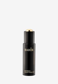 Schwarze zylindrische Flasche mit einem goldenen Deckel, auf dem der Text "BABOR 3D Firming Serum Foundation" in goldener Schrift zu sehen ist. Glatte, glänzende Oberfläche.