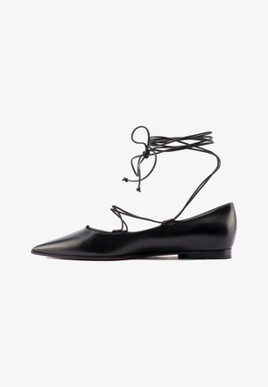 Scarpa flat in pelle nera con punta appuntita, fianchi intagliati e lacci avvolgenti. Texture liscia e design minimalista con tacco basso.