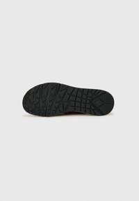 Semelle extérieure en caoutchouc noir avec des motifs de grip texturés, présentant un design en zigzag et une zone de orteil arrondie pour une traction et une durabilité accrues.