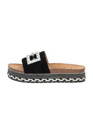 Sandale à glissière en suède noir avec une boucle ornée de cristaux, plateforme superposée avec des détails tressés noir et blanc, semelle plate.