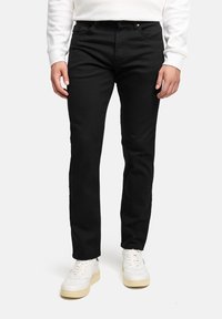 Jeans neri in denim con vestibilità slim, design a cinque tasche e dettagli di cucitura sottili, indossati con sneakers bianche e una felpa leggera.