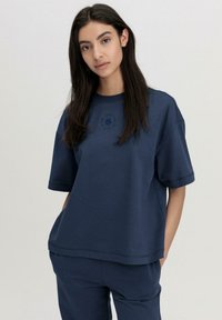 Navyblaues T-Shirt mit kurzen Ärmeln und Rundhalsausschnitt in lockerer Passform. Mit besticktem Design auf der Brust und weichem Baumwollmaterial.