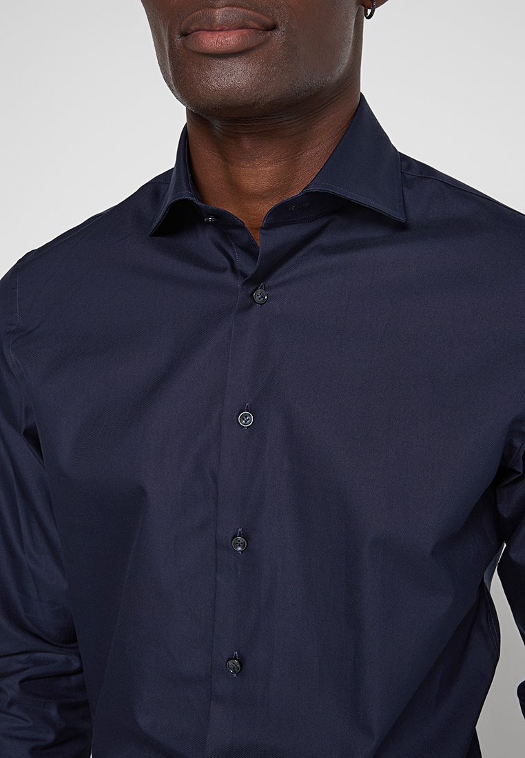 Granatowa koszula z długim rękawem, wykonana z gładkiego materiału, z klasycznym kołnierzykiem i sześcioma pasującymi guzikami z przodu.