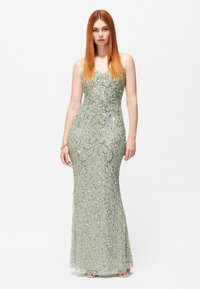 Abito da sera lungo verde con paillettes, dal taglio aderente, scollatura a V e intricati motivi in perline su tutto il vestito. Spalline regolabili.
