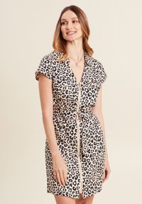 Leopardenmuster-Kleid mit kurzen Ärmeln, einem Reißverschluss vorne und einem taillierten Gürtel in Beige und Schwarz. Es hat zwei Brusttaschen und eine glatte Stofftextur.