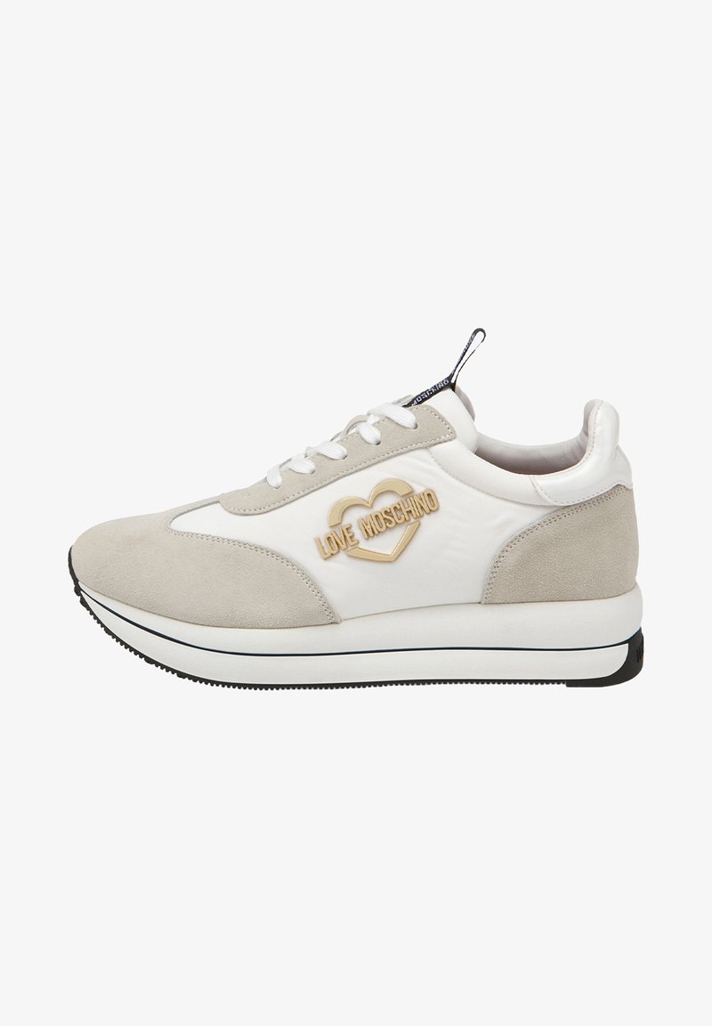 Sneakers blanches et gris clair avec un dessus en daim et synthétique, logo en forme de cœur en or, lacets blancs, semelle noire, et accents de design subtils.