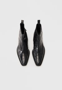 Schwarze Fällt-Krokodil-Leder-Ankle Boots mit spitzer Zehenform, seitlichem Reißverschluss und strukturiertem Finish. Glatter schwarzer Absatz.