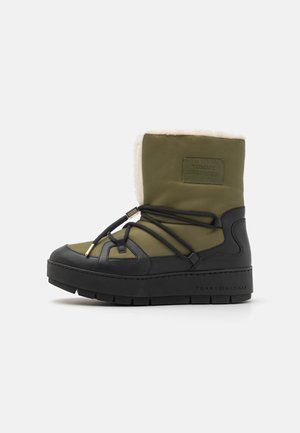 Botte d'hiver en vert olive et noir avec semelle épaisse, doublure en polaire, lacets sur les côtés et logo Tommy Hilfiger sur le dessus et la semelle.