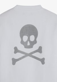White fabric with a glittery silver skull and crossbones design centered below a ribbed neckline.