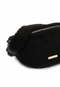 Czarna torebka na ramię o teksturze polarowej z srebrnym zamkiem błyskawicznym i regulowanym paskiem, z małą prostokątną metką marki.