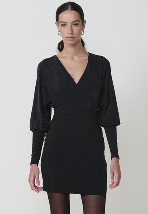 Vestido negro con escote en V, mangas largas y silueta ajustada. Fabricado en una tela brillante con una apariencia texturizada.