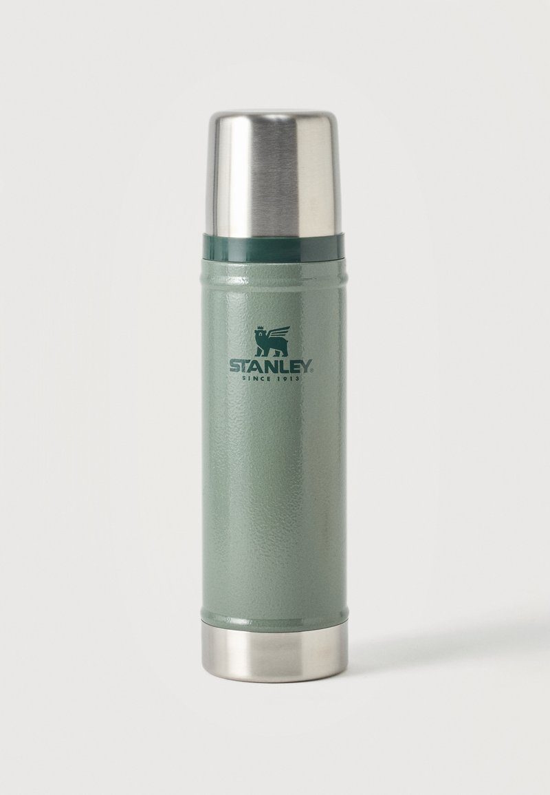 Πράσινο θερμός Stanley με ασημί καπάκι και βάση, όρθιο σε απλό φόντο.