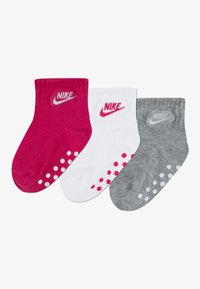 Detské ponožky Nike v ružovej, bielej a sivej farbe, s rebrovanými manžetami, detailom s logom a gumovými bodkami na podrážkach pre lepšiu priľnavosť.