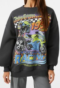 Sudadera negra con impresiones gráficas vibrantes de motocicletas, llamas y texto. Puños y dobladillo acanalados, corte oversize, material de mezcla de algodón.
