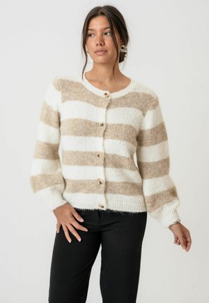 Cardigan stripat crem și bej, realizat din material moale și texturat, cu decolteu rotund, butoni în față și mansete cu nervuri. Stilizat cu pantaloni negri.