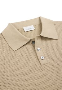 Beig polo-skjorta med texturerad stickad design, platt krage och treknappstoppning. Har två silverfärgade knappar och en etikett med 'PROFUOMO'.