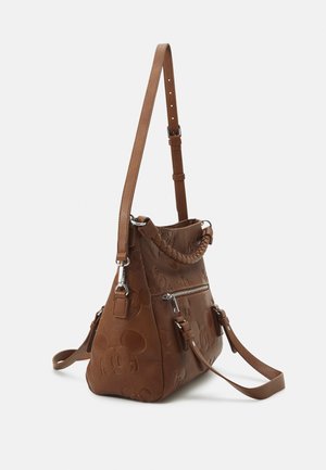 Brown leather backpack with embossed Mickey Mouse faces, braided handle, adjustable shoulder straps, and a zippered front pocket.