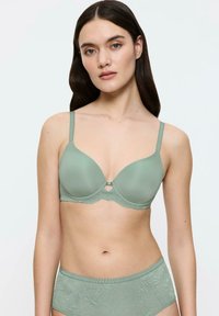 Sujetador acolchado de color verde claro con tirantes ajustables, detalles de encaje a lo largo de la banda y un detalle en forma de llave en el centro. Braguitas de cintura alta a juego.
