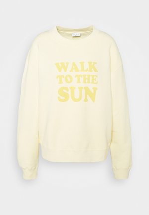 Jasnożółta bluza z długimi rękawami z dużym, bladożółtym napisem "WALK TO THE SUN" na przodzie.