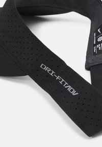 Črna Dri-FIT traka za glavo s perforiranim teksturo. Na sprednji strani se ponaša s srebrnim logotipom "DRI-FIT/ADV". Mehka in elastična materiala za udobje.