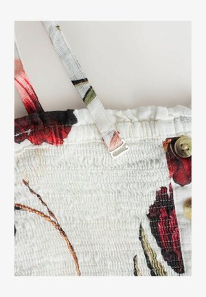 Weißer Stoff mit geraffter Textur, verstellbarem Schulterriemen, floralem rot-schwarzem Druck und beigen Knöpfen an der Seite.