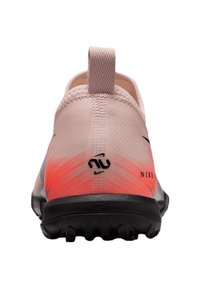 Scarpa sportiva Nike di colore rosa chiaro con un gradiente arancione. Presenta una tomaia testurizzata, una linguetta per il tallone e una suola nera con segni di trazione.