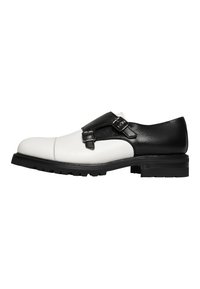 Schwarze und weiße Lederschuhe mit runder Spitze, doppelten Schnallenakzenten und einer strukturierten Oberfläche im schwarzen Teil. Gummisohle.