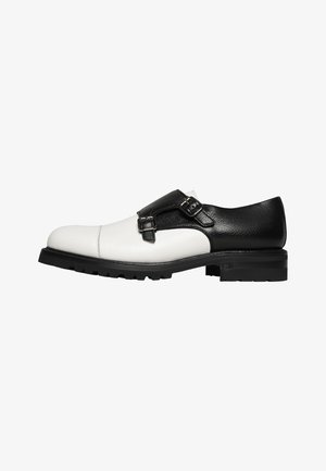 Leren schoenen in zwart en wit, met een ronde neus, dubbele gesp-accenten en een gestructureerde afwerking op het zwarte gedeelte. Rubberen zool.