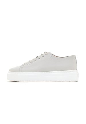 Light gray leather sneaker with rounded toe, lace-up front, thick white sole, and minimalistic design, featuring subtle stitching details.