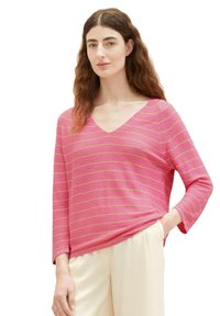 Rosa gestreifter Pullover mit V-Ausschnitt und 3/4-Ärmeln. Hat dünne gelbe Streifen, eine weiche Textur und eine lockere Passform. Kombiniert mit hellen Hosen.