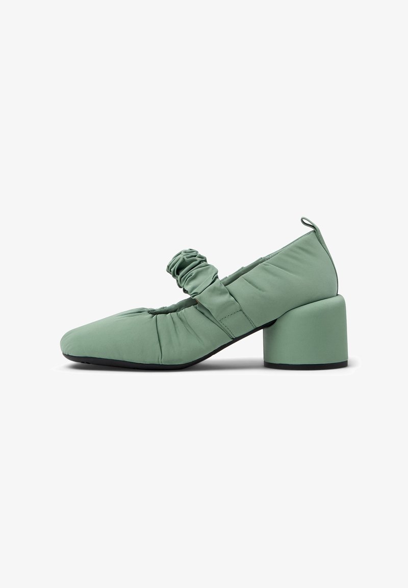Green fabric Mary Jane shoes with a square toe, gathered texture, and a chunky heel. Features a front strap with pleating detail.