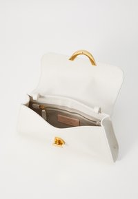 Borsa a tracolla in pelle bianca con chiusura in ottone dorato. L'esterno testurizzato presenta un interno foderato con una tasca con zip e un'etichetta del marchio.