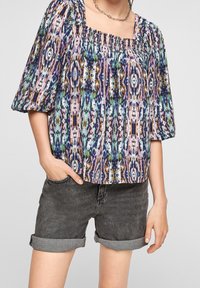 Flerfärgad mönstrad blus med fyrkantig halsringning, samlad textur och puffärmar, i kombination med rullade svarta denimshorts.