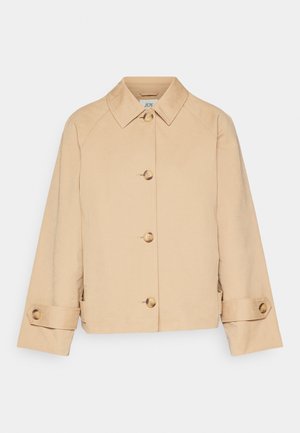 Giacca corta beige realizzata in un tessuto liscio, con colletto classico, chiusura frontale con bottoni e bottoni dorati sulle maniche.