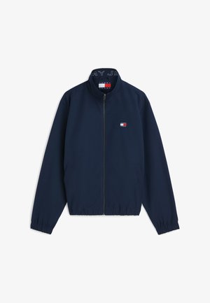 Marineblaue Jacke mit Reißverschluss und elastischen Bündchen, mit einem kleinen Tommy Jeans-Logo auf der Brust und einer Markenkennzeichnung im Kragen.