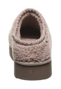 Light pink shearling slip-on shoe with a rounded toe, plush texture, and a thick beige sole; lacks visible hardware or embellishments.