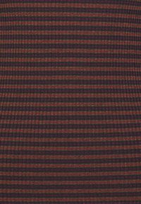 Ribbade tyger med smala horisontella ränder i mörkröd, brun och marinblå. Texturen verkar mjuk och något elastisk.