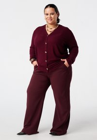 Bordeaux cardigan met hartvormige knopen, gecombineerd met bijpassende bordeaux ruime broek. Soepele textuur, subtiele ontwerpdetailleringen.