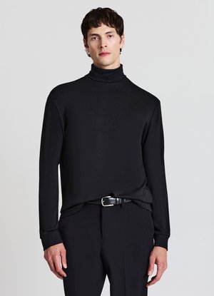 Maglione nero a collo alto realizzato in tessuto liscio, con maniche lunghe e design aderente, abbinato a pantaloni neri su misura e una cintura.